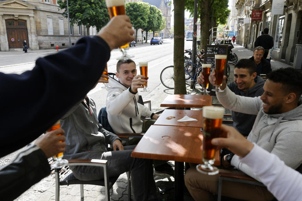 People toast with beers at a café terrace Wednesday, May, 19, 2021 in Strasbourg, eastern France. It's a grand day for the French. Café and restaurant terraces are reopening Wednesday after a shutdown of more than six months deprived people of what feels like the essence of life — sipping coffee and wine with friends outdoors — to save lives during the coronavirus pandemic. (AP Photo/Jean-Francois Badias)