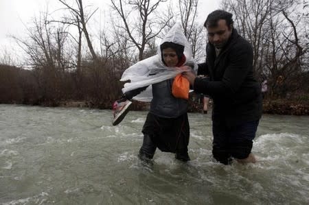 Refugees and migrants cross a river near the Greek-Macedonian border to return to Greece, after an unsuccessful attempt to enter Macedonia, west of the village of Idomeni, Greece, March 15, 2016. REUTERS/Alexandros Avramidis