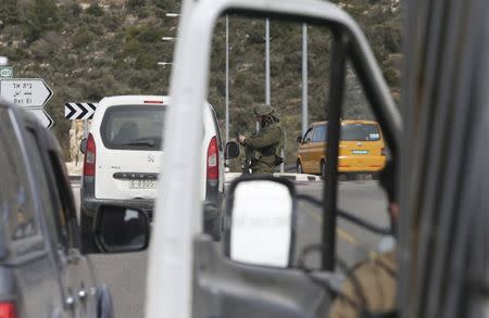 An Israeli soldier checks the identity card of a Palestinian at an Israeli checkpoint leading to the West Bank city of Ramallah February 1, 2016. REUTERS/Mohamad Torokman