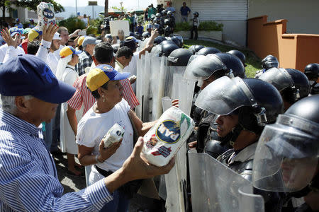 Opposition supporters hold packages of PAN corn flour in front of riot police during a rally against Venezuelan President Nicolas Maduro's government and to commemorate the 59th anniversary of the end of the dictatorship of Marcos Perez Jimenez in San Cristobal, Venezuela January 23, 2017. REUTERS/Carlos Eduardo Ramirez