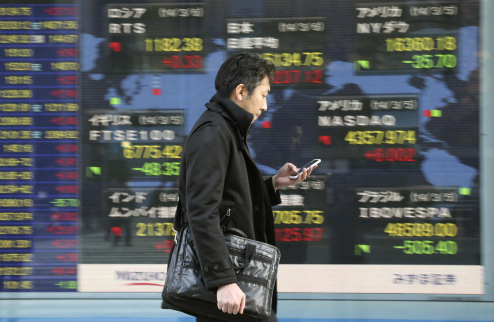 A man walks by an electronic stock board of a securities firm in Tokyo, Thursday, March 6, 2014. Shares were mostly higher in Asia on Thursday as the standoff over Ukraine between Russia and the West continued to ease and the yen weakened. (AP Photo/Koji Sasahara)