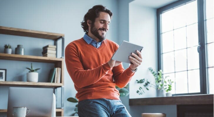 A man smiles as he looks over his dividend distributions. Vanguard recently announced the estimated supplemental distributions that it will pay to shareholders in March 2022.