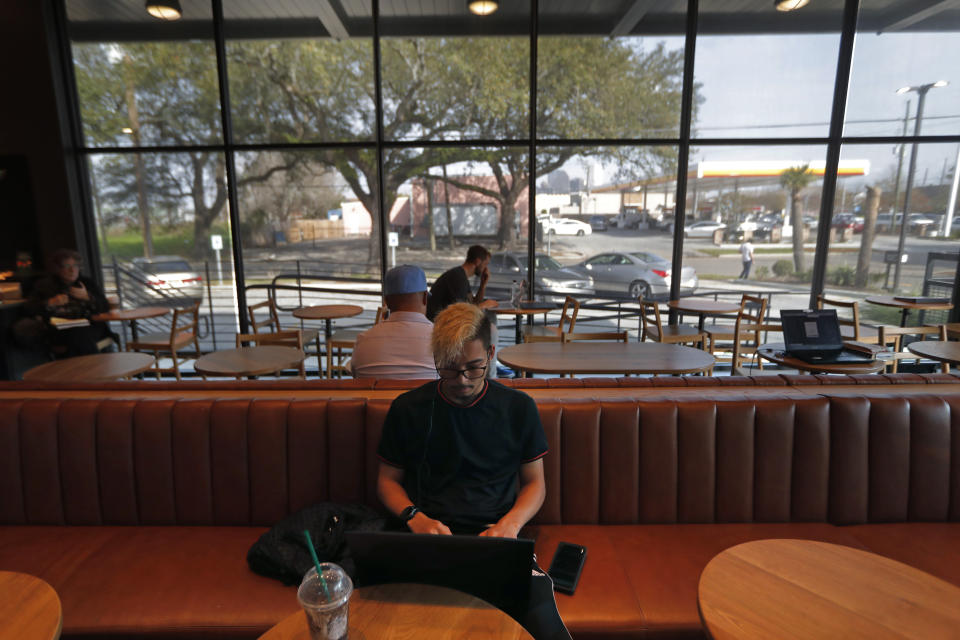 Customer Ousmane Wilson works on his computer at a Starbucks on South Claiborne Ave. in New Orleans, Thursday, Jan. 16, 2020. Starbucks, the home of the $4 latte, is expanding a program to open coffee shops in poor neighborhoods. The Seattle-based company plans to open or remodel 85 stores by 2025 in rural and urban communities across the U.S. Each store will have event space, and Starbucks will work with local United Way chapters to offer programs like youth job training. (AP Photo/Gerald Herbert)