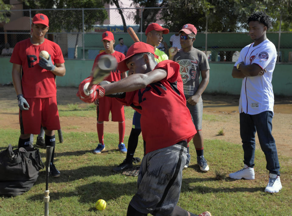 Members of the baseball school called ‘Los Cachorros de la Italia’ conduct hitting practice with Victor Robles, right, watching. This was the school that Washington Nationals player Victor Robles was discovered in the Dominican Republic. (Getty Images)