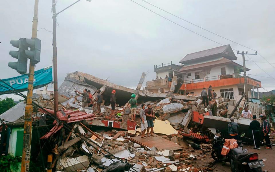 Residents inspect earthquake-damaged buildings in Mamuju, West Sulawesi - AP