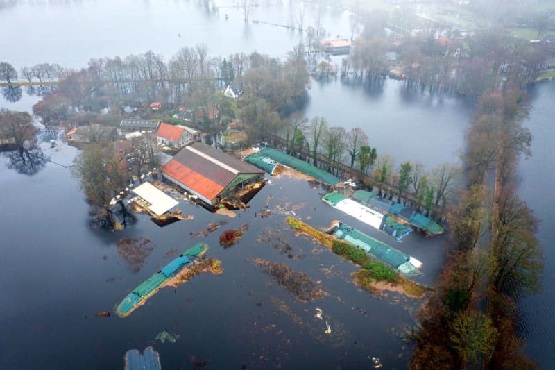 An aerial view taken by a drone shows a flooded farm. According to the forecasts of the German Weather Service (DWD), heavy rain is expected to continue, so the situation remains tense. Sina Schuldt/dpa