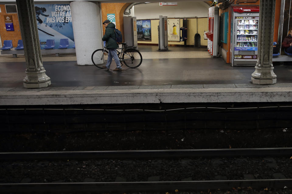 A passenger walks with his bicycle on empty platform of a RER suburb subway, in Paris, Sunday, Dec. 8, 2019 on the fourth day of nationwide strikes that disrupted weekend travel around France. (AP Photo/Francois Mori)