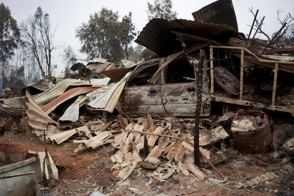 Charred remains of a home burned in a wildfire sit in a pile in Tome, Chile, Saturday, Feb. 4, 2023. Forest fires are spreading in southern and central Chile, triggering evacuations and the declaration of a state of a state of catastrophe on La Araucania region. (AP Photo/Matias Delacroix)