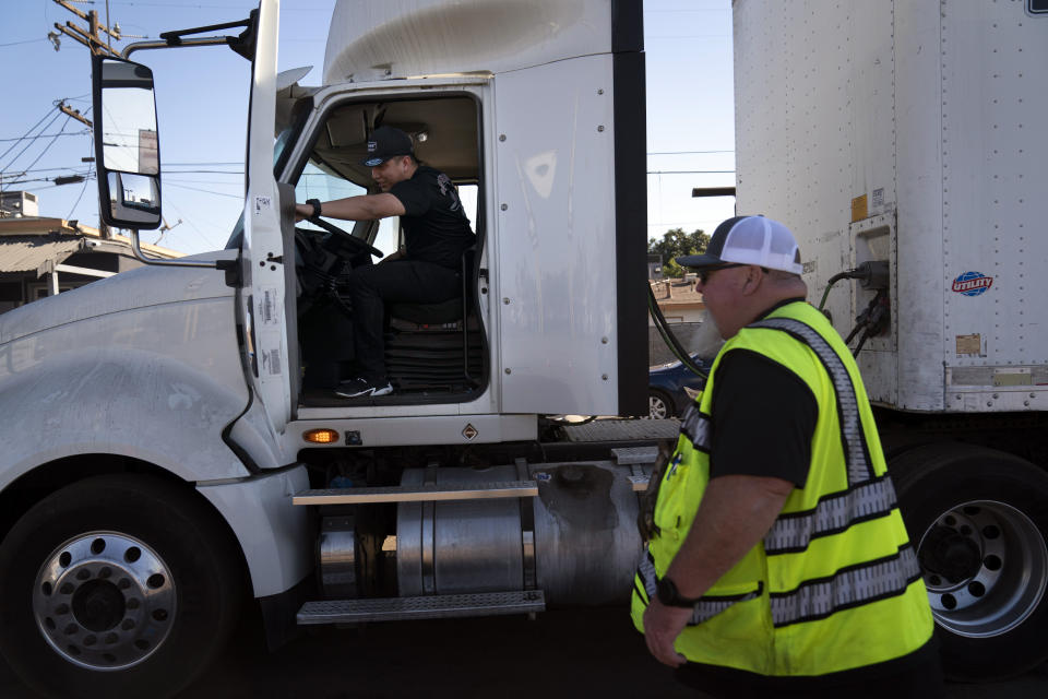 Student driver Luis Barrientos, left, gets on a truck as instructor Daniel Osborne watches at California Truck Driving Academy in Inglewood, Calif., Monday, Nov. 15, 2021. Amid a shortage of commercial truck drivers across the U.S., a Southern California truck driving school sees an unprecedented increase in enrollment numbers. The increase is big enough that the school is starting an evening class to meet the demand, according to Tina Singh, owner and academy director of California Truck Driving Academy. "I think that's only going to continue because there's a lot of job opportunities. We have over 100 active jobs on our job board right now," said Singh. The companies that normally would not hire drivers straight out of school are "100 percent" willing to hire them due to shortage issues, the director added. (AP Photo/Jae C. Hong)