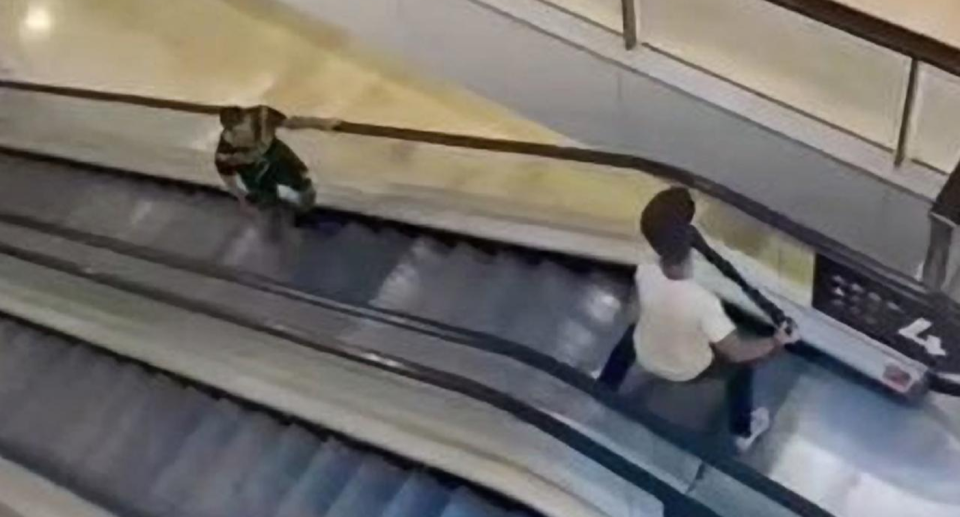 Damien Geurot at the top of an escalator confronting the kinfeman.