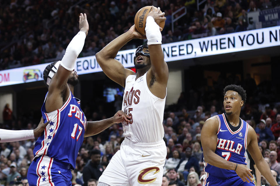 Cleveland Cavaliers guard Donovan Mitchell (45) shoots against Philadelphia 76ers guard Buddy Hield (17) and guard Kyle Lowry (7) during the second half of an NBA basketball game Friday, March 29, 2024, in Cleveland. (AP Photo/Ron Schwane)
