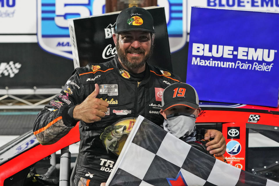 Martin Truex Jr. gives a thumbs-up as he celebrates with a fan after winning a NASCAR Cup Series auto race at Martinsville Speedway in Martinsville, Va., Sunday, April 11, 2021. (AP Photo/Steve Helber)