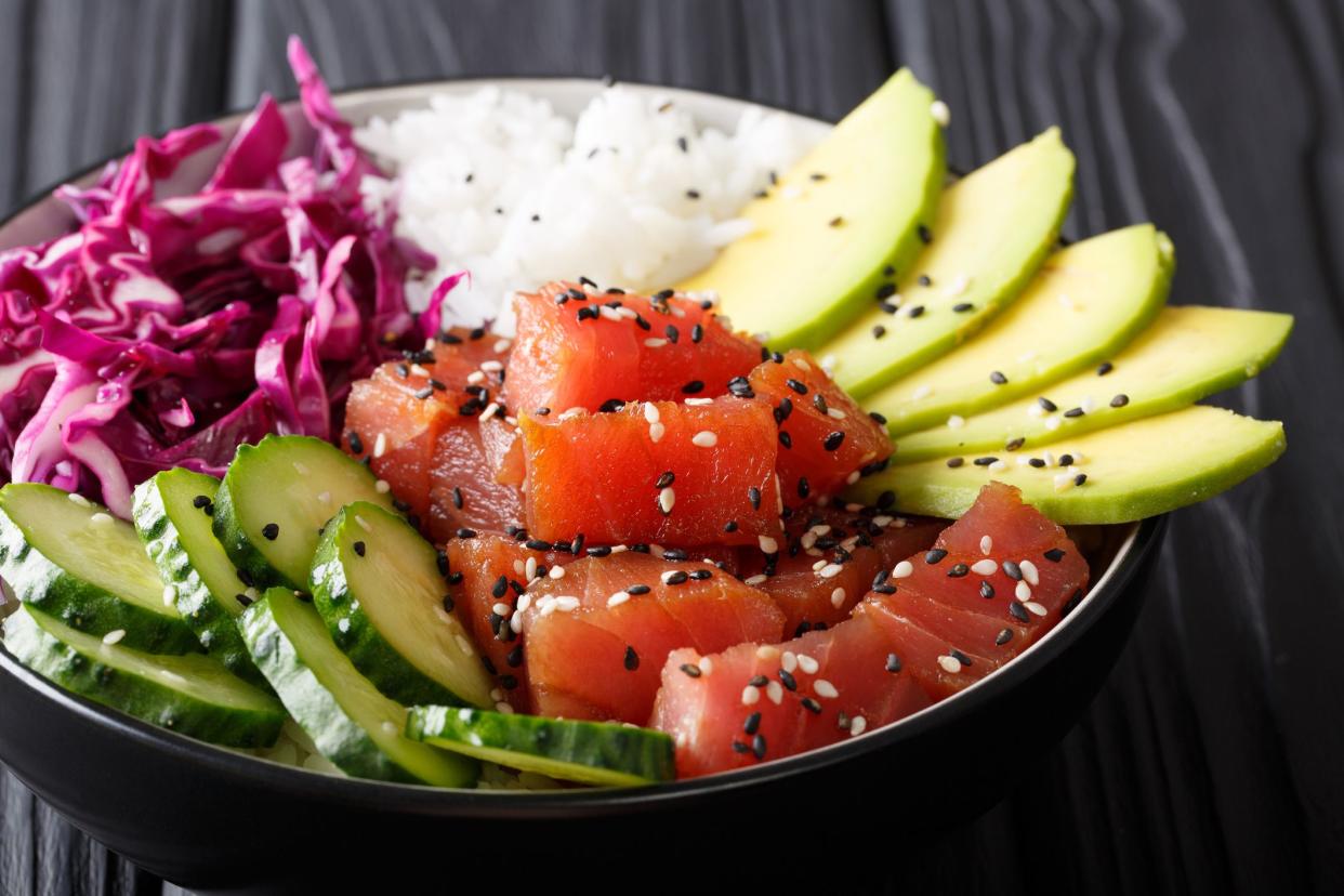 Raw Organic Ahi Tuna Poke Bowl with Rice and Veggies close-up on the table. Horizontal