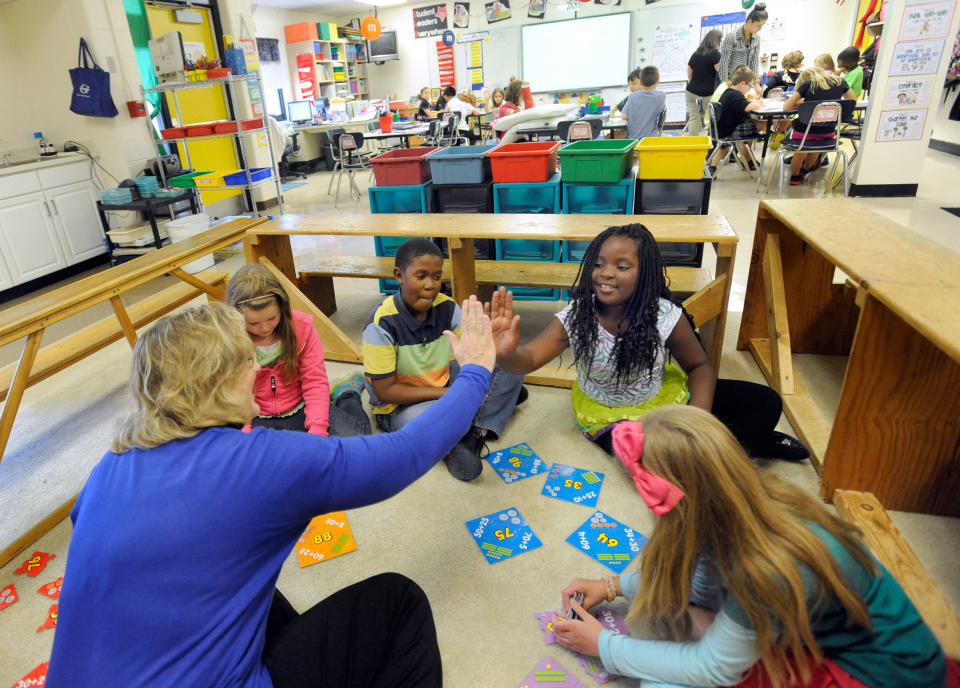 Third-grade teacher Sherry Frangia, left, high-fives student Jayla Hopkins during a math lesson at Silver Lake Elementary School in Middletown, Del. Tuesday, Oct. 1, 2013. Silver Lake has begun implementing the national Common Core State Standards for academics. (AP Photo/Steve Ruark)