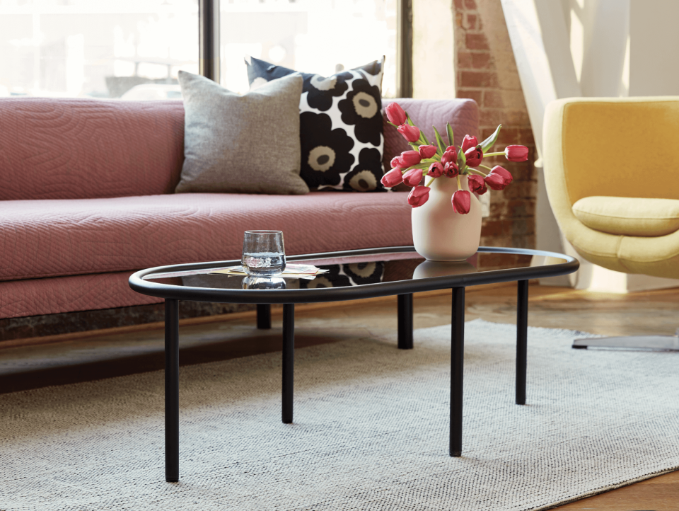 pink couch with floral throw pillows and white carpet and black Tubular Coffee Table (Photo via EQ3)