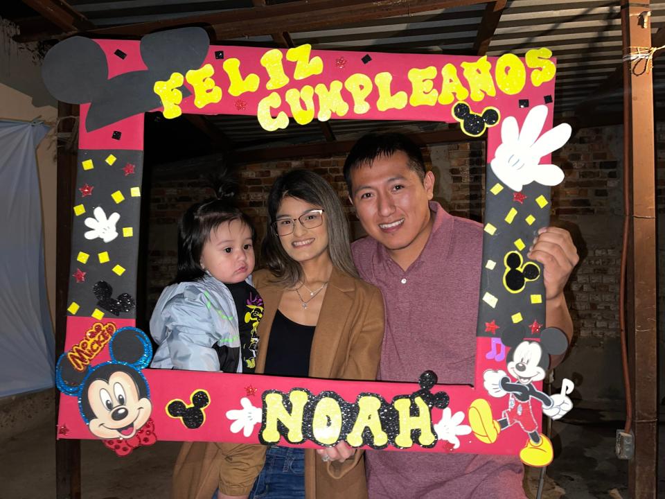 Yarianna Martinez, Jaime Avalos, and their son Noah pose for a birthday in a frame that says "Feliz Cumpleanos."