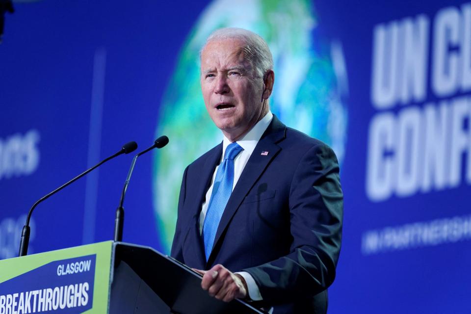 President Biden stands at a podium with two microphones and sign that reads Glasgow Breakthroughs in front of a backdrop of a globe.