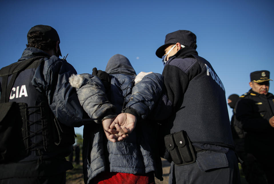 A man is detained by police during the eviction of a squatters camp in Guernica, Buenos Aires province, Argentina, Thursday, Oct. 29, 2020. A court ordered the eviction of families who have been squatting at the camp since July, but the families say they have nowhere to go amid the COVID-19 pandemic. (AP Photo/Natacha Pisarenko)