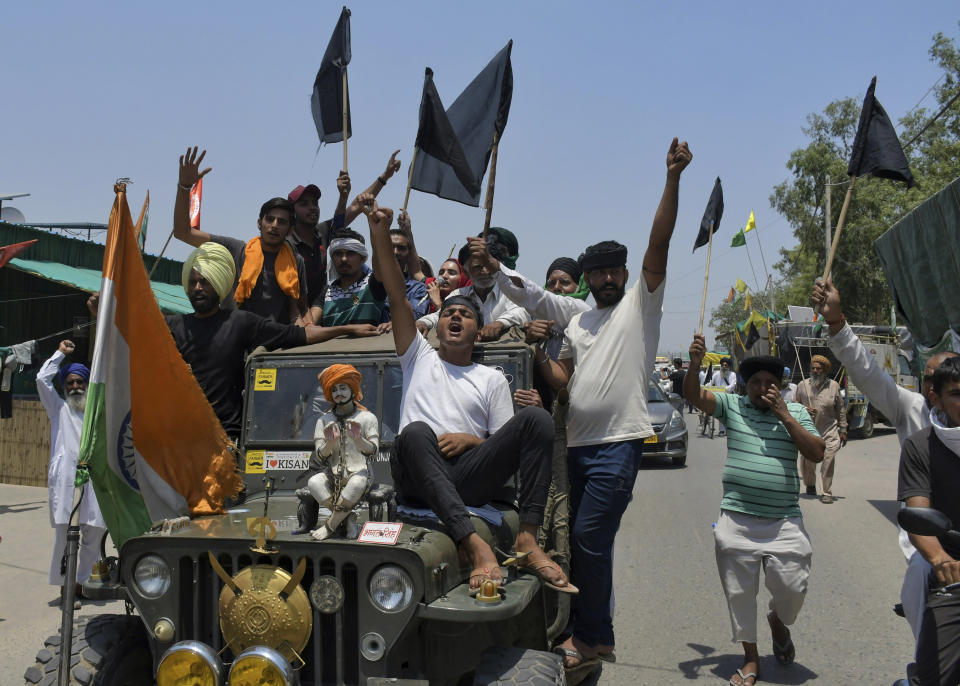 Farmers, some carrying black flags, on a vehicle during a protest in Ghazipur, outskirts of New Delhi, India, Wednesday, May 26, 2021. Indian farmers demanding the government repeal new agriculture laws they say will devastate their livelihoods marked their protest movement's sixth month Wednesday by flying black banners on the cars and tractors and burning effigies of the prime minister. (AP Photo/Ishant Chauhan)