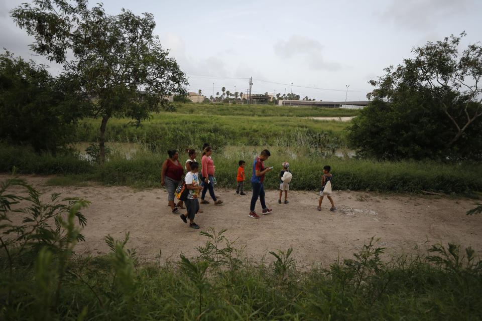 Migrants from Honduras, Nicaragua, and Mexico walk with two local friends along the Rio Grande, before they sleep for the night on the pavement at the entrance to the bridge that crosses to Brownsville, Texas, in downtown Matamoros, Tamaulipas state, Mexico, Wednesday, June 26, 2019. Amid limited migrant shelter offerings, migrants who don't have money for hotels or to rent a room are sleeping outside, as they wait their turn to request asylum in the U.S. (AP Photo/Rebecca Blackwell)