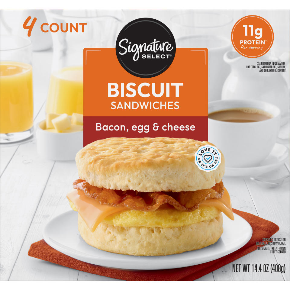 Advertisement showing Signature Select's bacon, egg, and cheese biscuit sandwiches with a glass of orange juice and coffee mug in the background