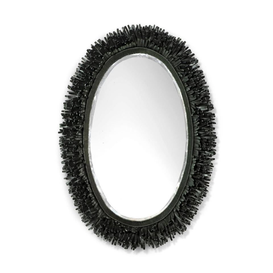 black oval mirror with short fringe encircling it