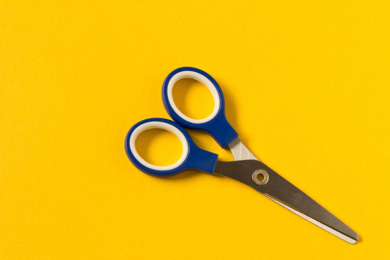 Scissors on an yellow background. Colored baby scissors
