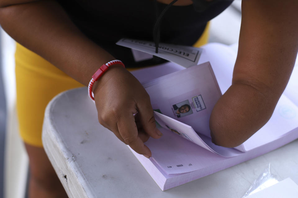 A poll worker with a missing hand, grabs ballots during local and legislative elections, at a polling place in the Zona Rosa district of San Salvador, El Salvador, Sunday, Feb. 28, 2021. Sunday's elections in El Salvador are seen as a referendum on whether to break the congressional deadlock that has tied the hands of upstart populist President Nayib Bukele. (AP Photo/Salvador Melendez)