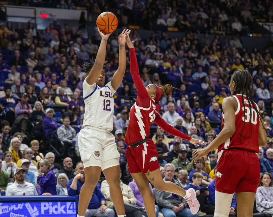 LSU guard Mikaylah Williams (12) shoots for three points over Arkansas guard Makayla Daniels, center, in the second period of an NCAA college basketball game Sunday, Jan. 21, 2024, in Baton Rouge, La. (Michael Johnson/The Advocate via AP)