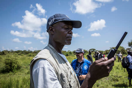 A World Food Programme employee uses a satellite phone to coordinate a U.N's World Food Programme (WFP) food aid air drop near the town of Katdalok, in Jonglei State of South Sudan July 30, 2018. REUTERS/Denis Dumo