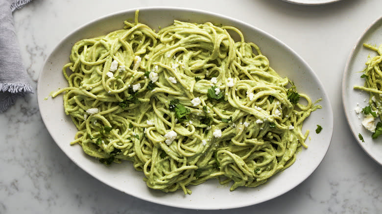 spaghetti with green sauce on speckled serving dish