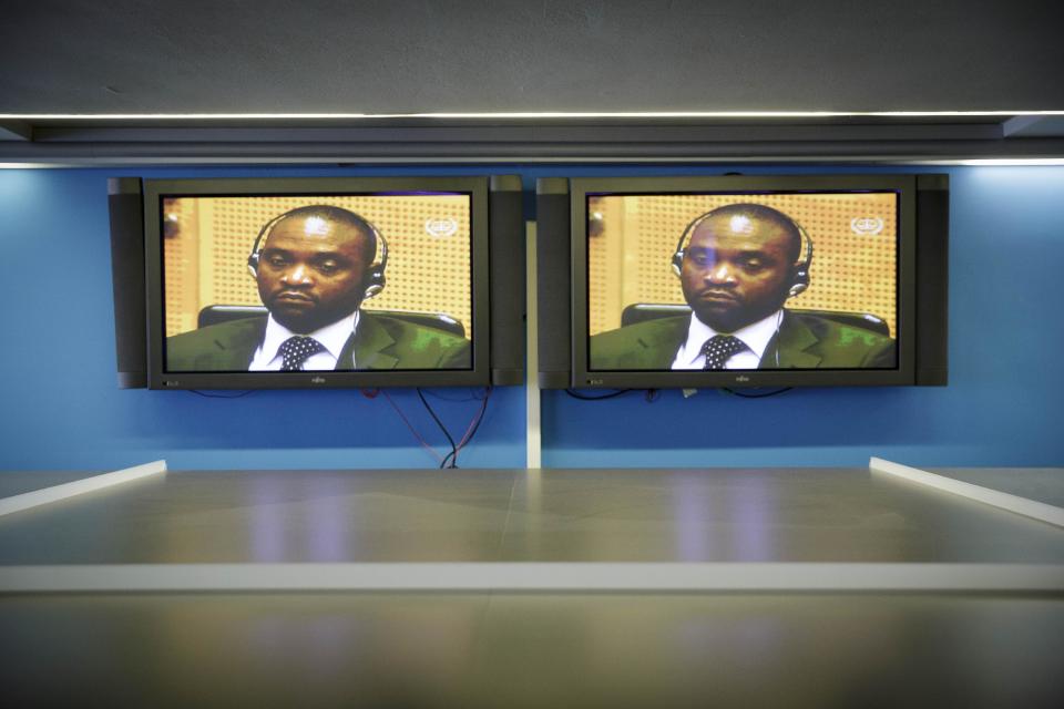 Images of Germain Katanga are broadcast on TV in the pressroom of the International Criminal Court (ICC) in The Hague, Netherlands, Friday March 7, 2014. The ICC has convicted rebel leader Germain Katanga of charges including murder and pillage during a deadly attack on a village in eastern Congo, but acquitted him of rape, sexual slavery and using child soldiers. Katanga showed no emotion as judges convicted him as an accessory in the attack on the strategic village of Bogoro on Feb. 24, 2003, in which some 200 civilians were hacked or shot to death. (AP Photo/Phil Nijhuis, Pool)