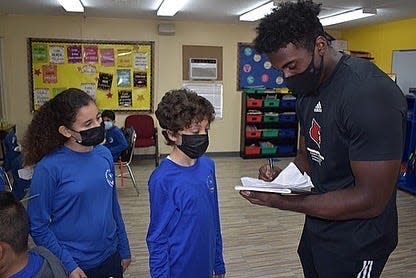 Louisville linebacker Yasir Abdullah takes pictures with a group of students at Nural Islam Academy.