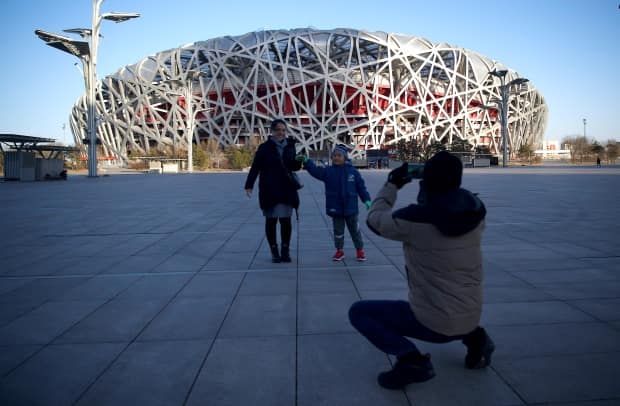 People take pictures in front of the Birds Nest stadium, the venue for opening and closing ceremonies for the 2022 Winter Olympics, in Beijing. (AFP via Getty Images - image credit)