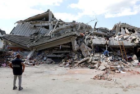 A rescuer stands in front of a collapsed building following an earthquake in Amatrice, central Italy. REUTERS/Ciro De Luca