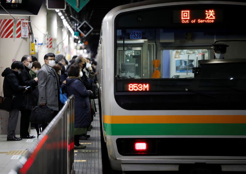 Commuters wearing protective face masks wait to enter a train on the way home, amid the coronavirus disease (COVID-19) outbreak in Tokyo