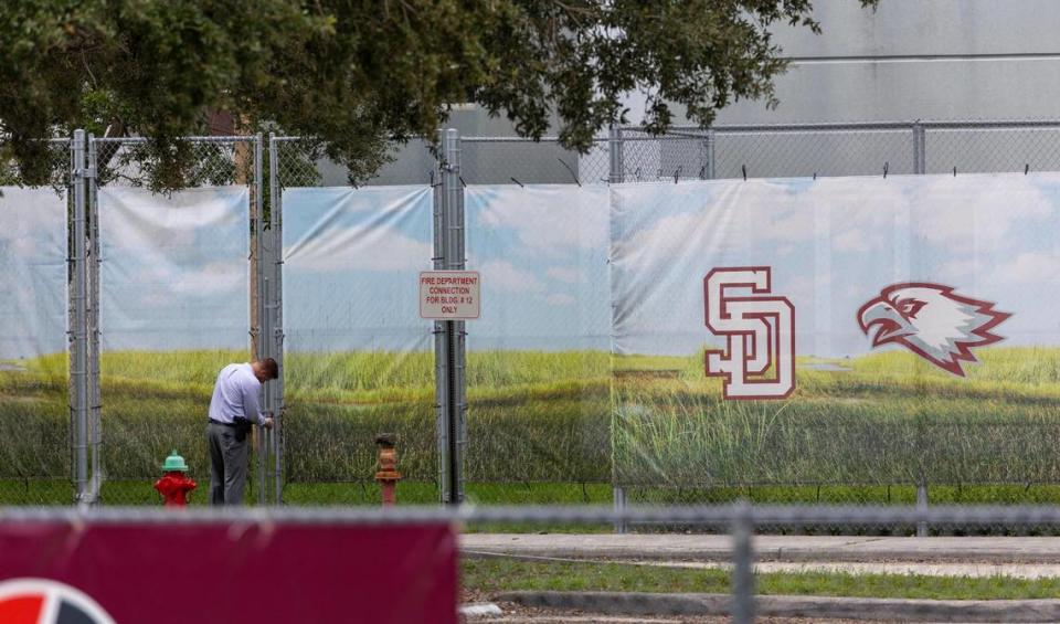 Parkland, Florida - July 5, 2023 - A man closes the gates to the fence surrounding the Freshman Building, the site of the shooting in February 14, 2018 where 17 people died. Family members of the shooting victims at Marjory Stoneman Douglas High School visited the scene of the crime. The building will be demolished now that the trials are over.