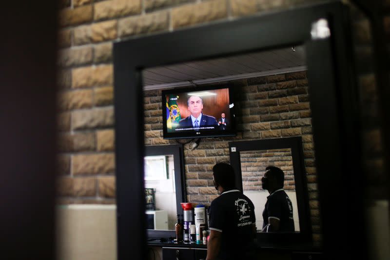 Brazil's President Jair Bolsonaro is seen on a tv screen in a barbershop as he speaks in a video recorded speech for the 75th session of the United Nations General Assembly, in Brasilia