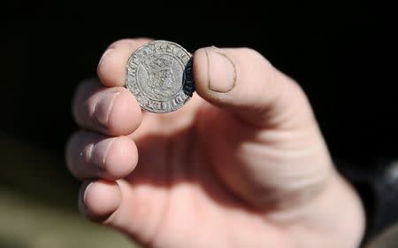 A mudlark shows a Henry VII coin that he excavated from the River Thames in London, Britain May 23, 2016. REUTERS/Neil Hall