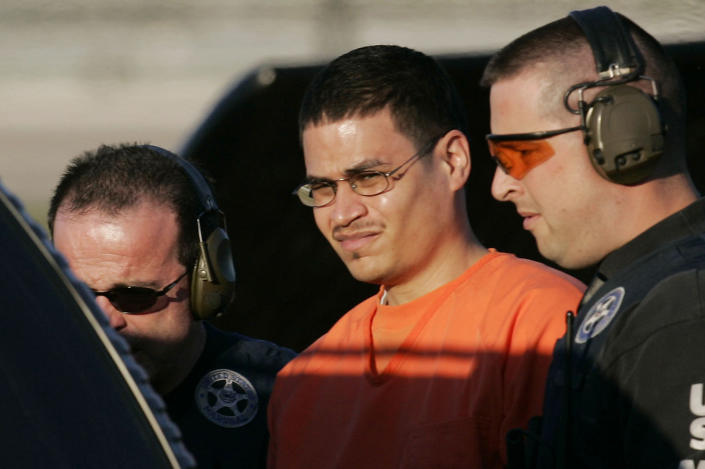 In this Jan. 5, 2006 file photo, Jose Padilla, center, is escorted to a waiting police vehicle by federal marshals near downtown Miami.  (AP Photo/J. Pat Carter, File)