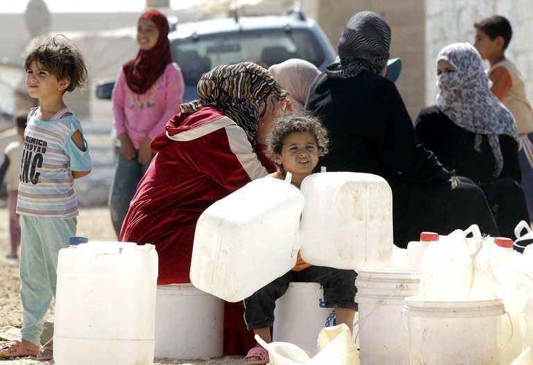 Syrian refugees wait to fill up plastic water containers at the Al-Zaatari refugee camp near the Jordanian city of Mafraq, some 8-kilometres from the Syrian border, on July 26, 2013. Jordanians were voting Tuesday in municipal elections with the impact of a massive influx of war refugees from neighbouring Syria on a struggling economy stoking voter resentment and apathy