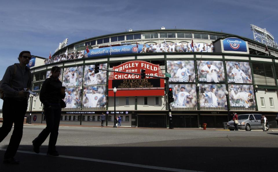 FILE - In this April 4, 2012 file photo, people walk by the Marquee at Wrigley Field, one day before the Chicago Cubs' home opener against the Washington Nationals in Chicago. All the baseball teams are based in major U.S. cities and many of the stadiums are situated in bustling downtown areas with engrossing things to do and savory places to eat when you aren't attending a game. These attractions should help the cause of baseball fans trying to recruit a spouse or other traveling teammates who may not appreciate the sublime pleasures of the game. (AP Photo/Nam Y. Huh, File)