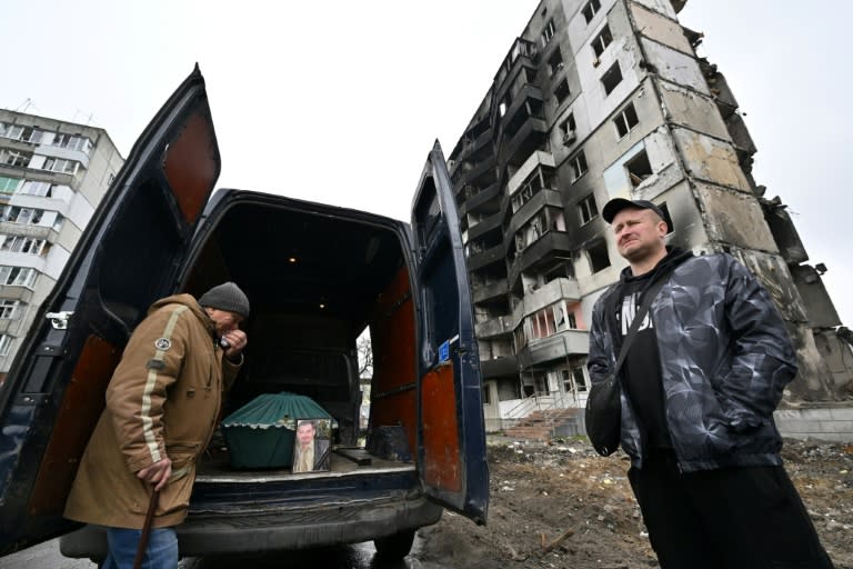 Un hombre llora junto a una furgoneta con el ataúd de su hijo, que murió por el colapso de un edificio tras un bombardeo ruso, en Borodianka, al noroeste de Kiev, el 21 de abril de 2022 (AFP/Sergei SUPINSKY)