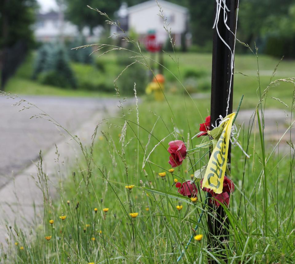 Police tape its tied on an 8th Avenue street sign Sunday near where a mass shooting occurred in East Akron; a memorial affixed to the sign had been placed there after an incident that preceded early Sunday's gunfire.