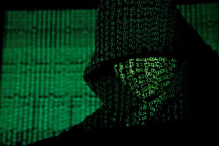 A projection of cyber code on a hooded man is pictured in this illustration picture taken on May 13, 2017. REUTERS/Kacper Pempel/Illustration