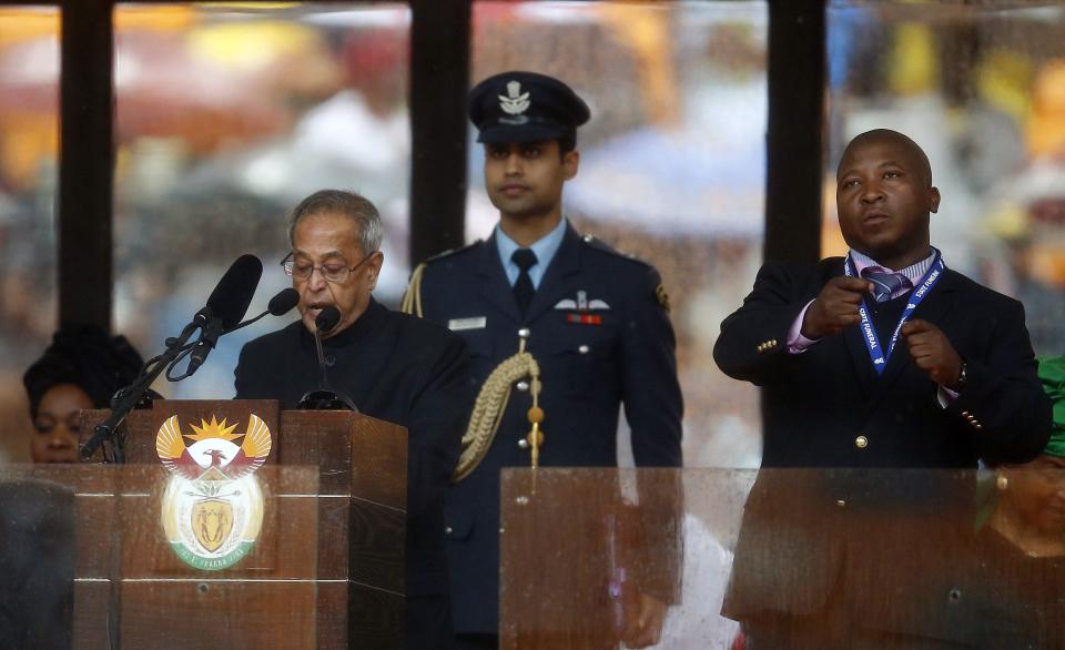 India's President Mukherjee speaks at the podium as a sign language interpreter punches air beside him during a memorial service for late South African President Nelson Mandela in Johannesburg