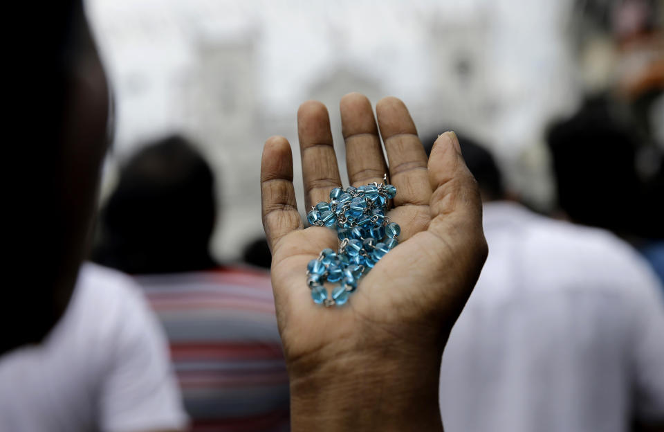 A Sri Lankan Catholic holds her rosary as she prays on a road during a brief holly mass held outside the exploded St. Anthony's Church marking the seventh day of the Easter Sunday attacks in Colombo, Sri Lanka, Sunday, April 28, 2019. Sri Lanka's Catholics on Sunday awoke preparing to celebrate Mass in their homes by a televised broadcast as churches across the island shut over fears of militant attacks, a week after the Islamic State-claimed Easter suicide bombings. (AP Photo/Eranga Jayawardena)