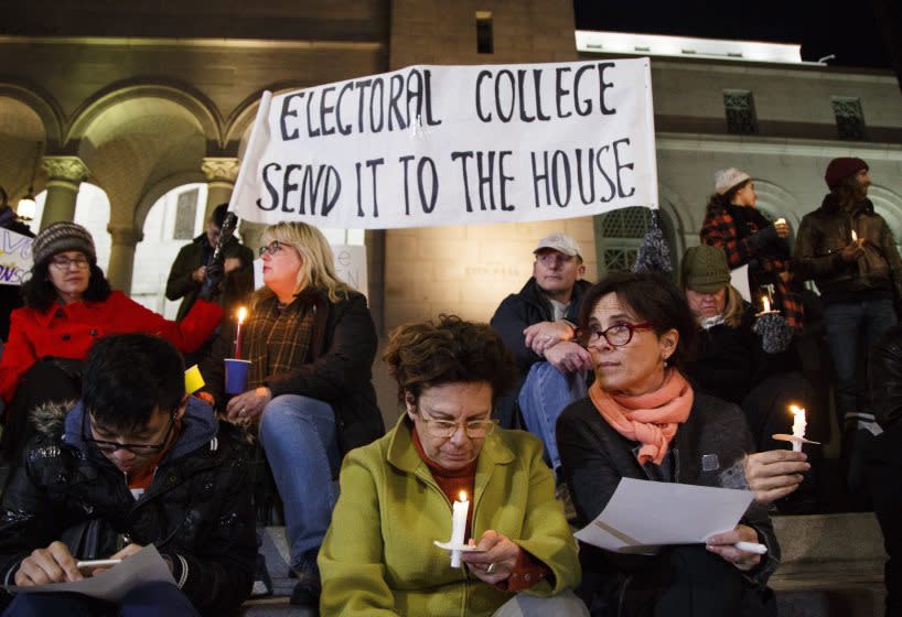 Protestors opposed to President-elect Donald Trump petition to the Electoral College on the eve of its vote during a candlelight vigil in Los Angeles.