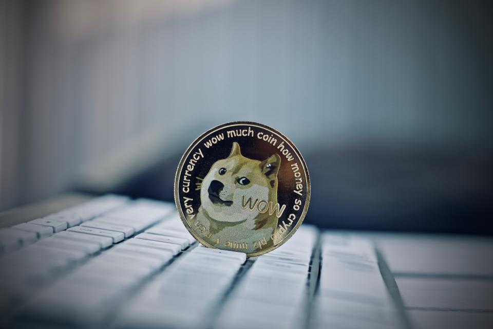 Digital currency physical metal dogecoin coin on white computer keyboaed.