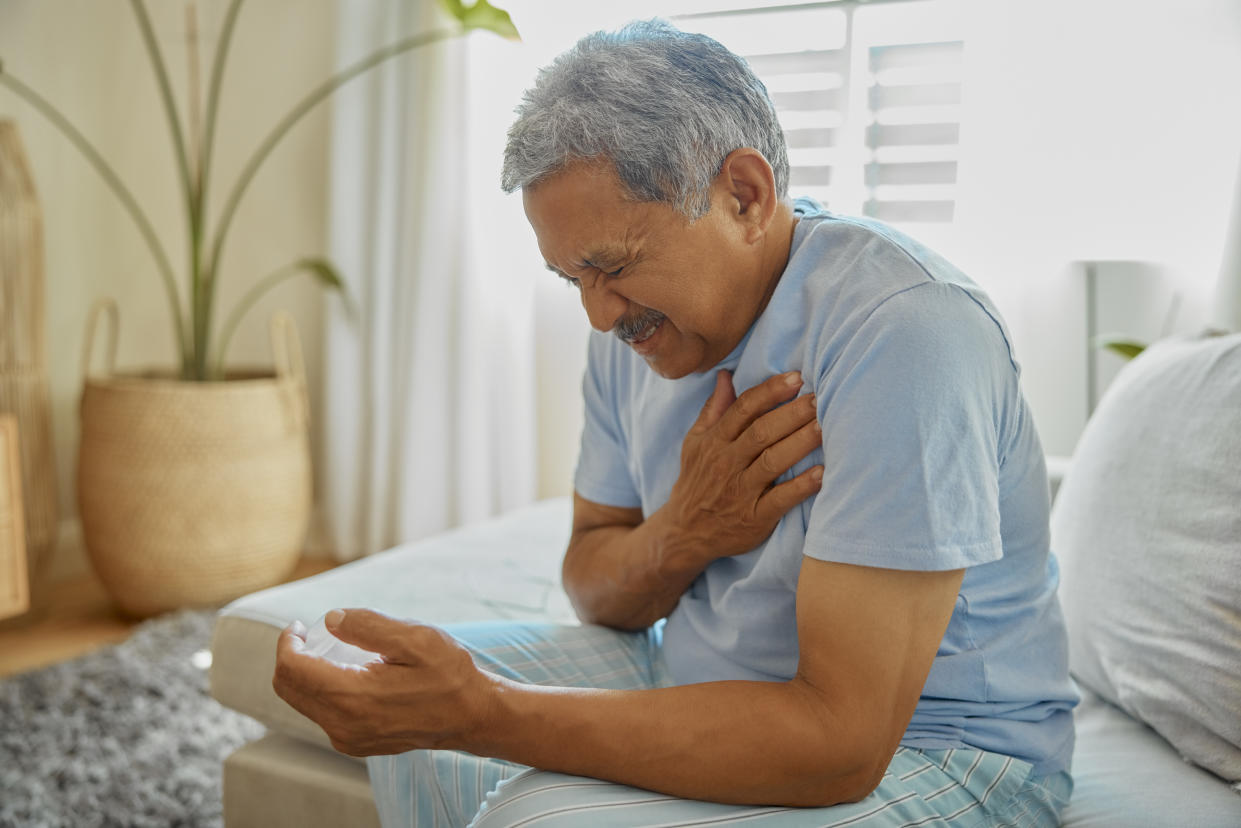 Elderly man, worry and heart attack in a bedroom from stress, anxiety or crisis in a nursing home. Chest pain, panic and senior male with problem, issue and disaster or emergency waking up in a bed